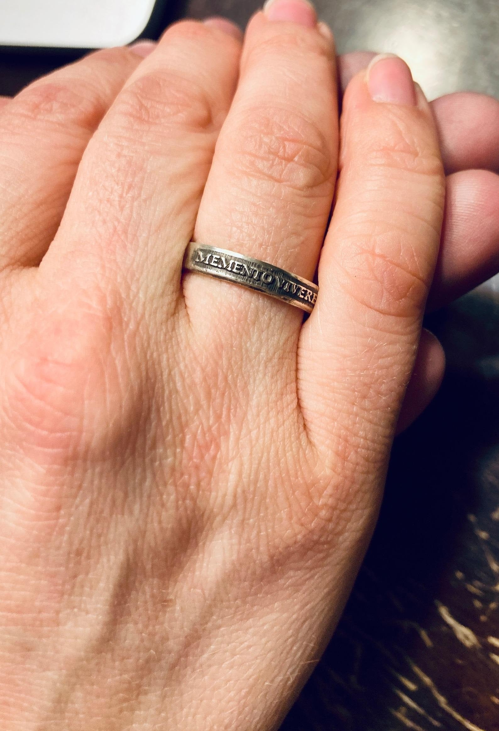 Close-up of raised Memento Vivere lettering on a sterling silver ring
