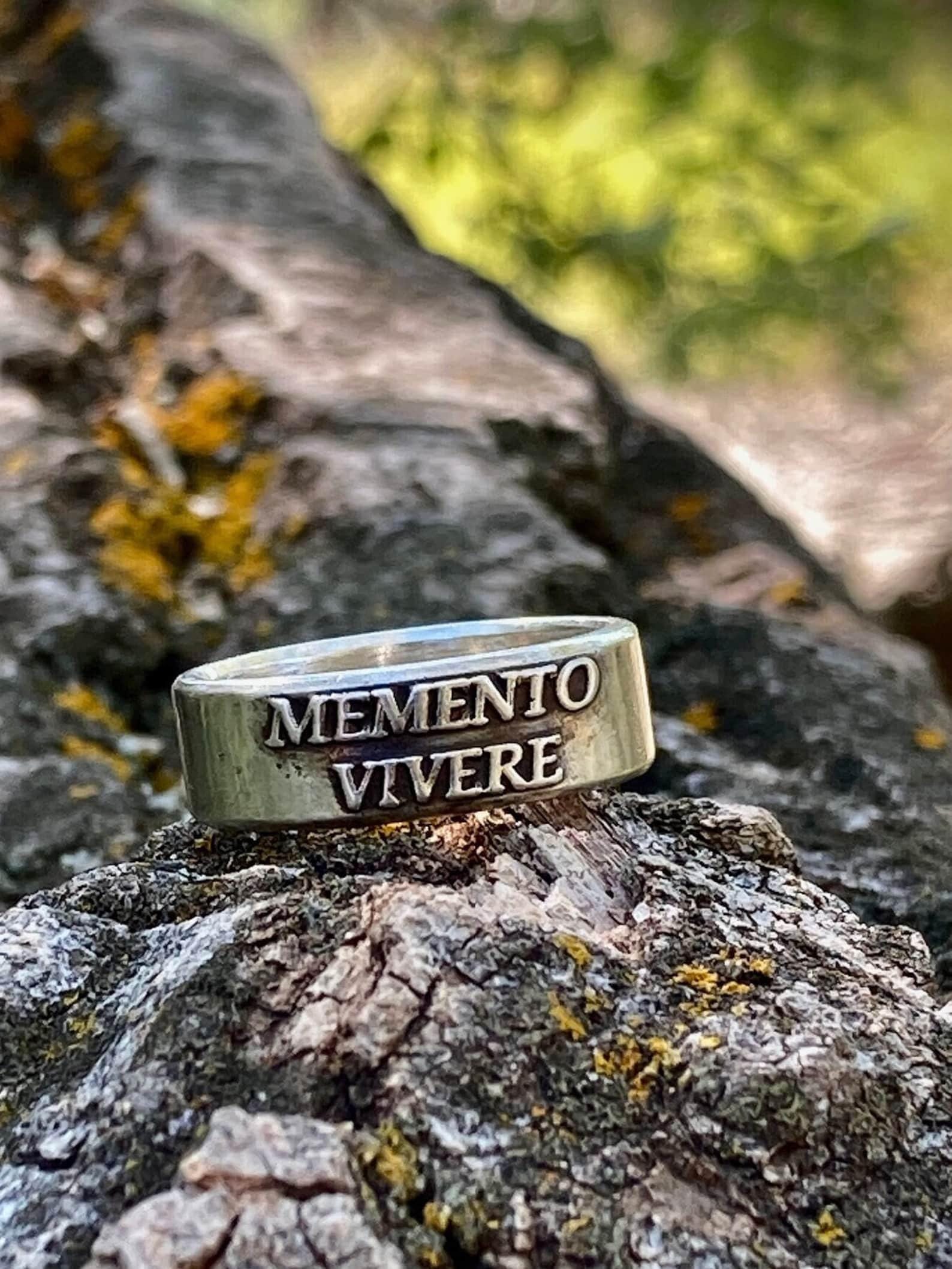 Memento Vivere sterling silver ring displayed on rustic bark
