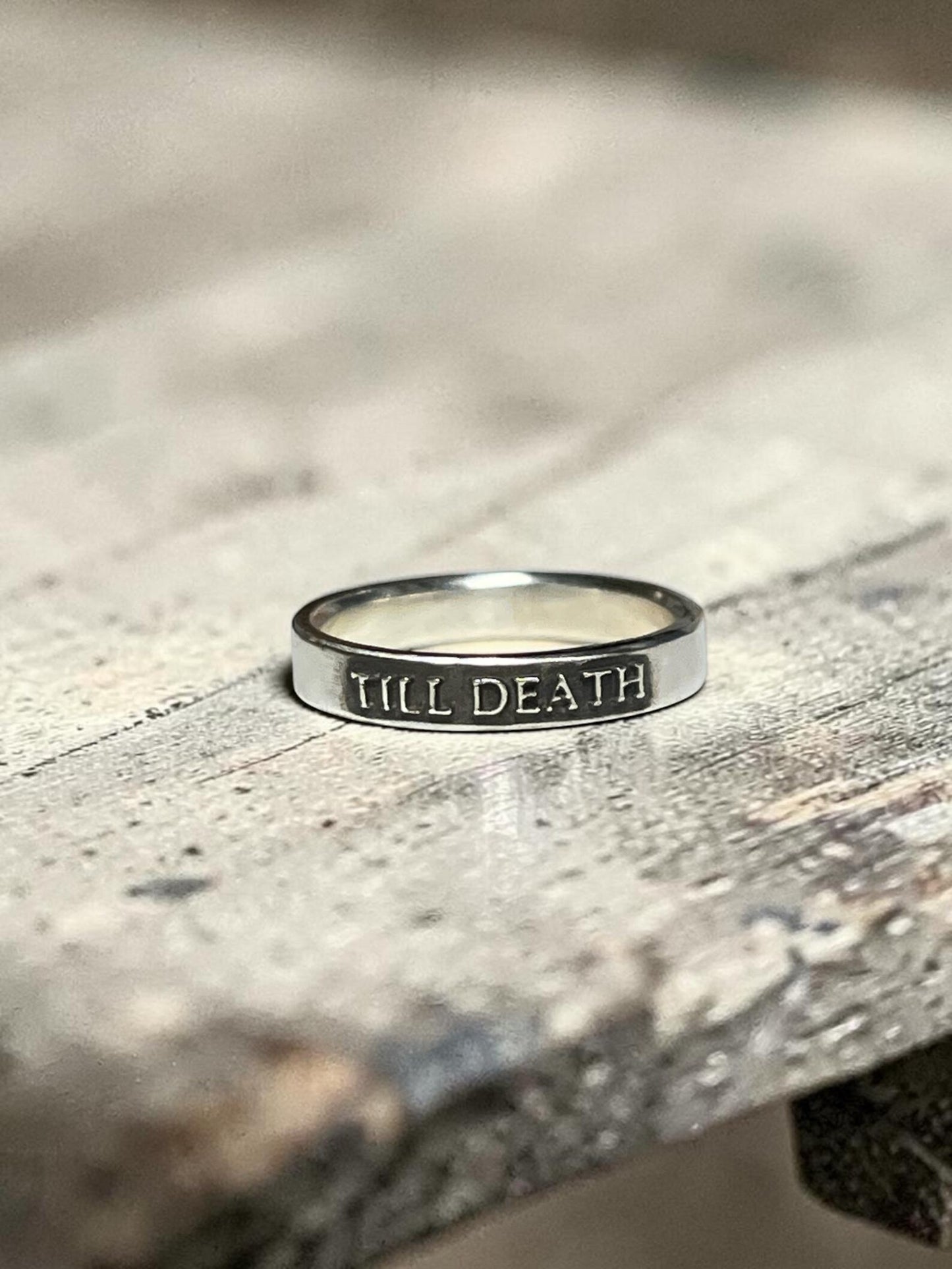 Till Death sterling silver ring on a textured surface