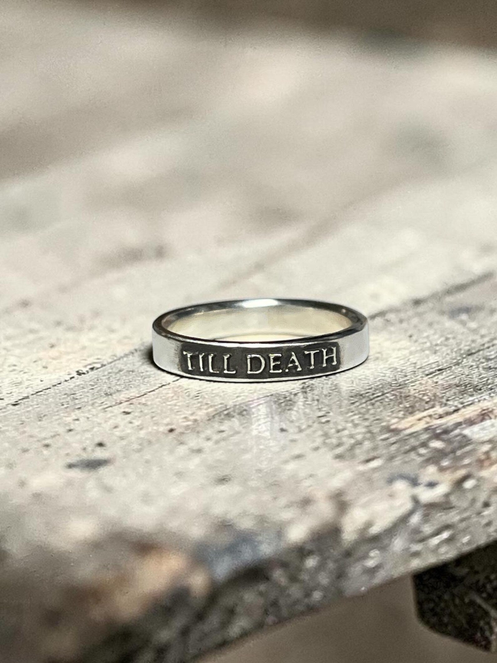 Till Death sterling silver ring on a textured surface