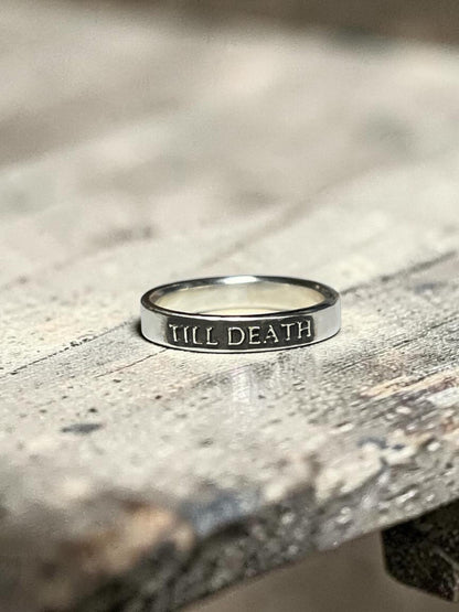Till Death sterling silver ring on a textured surface