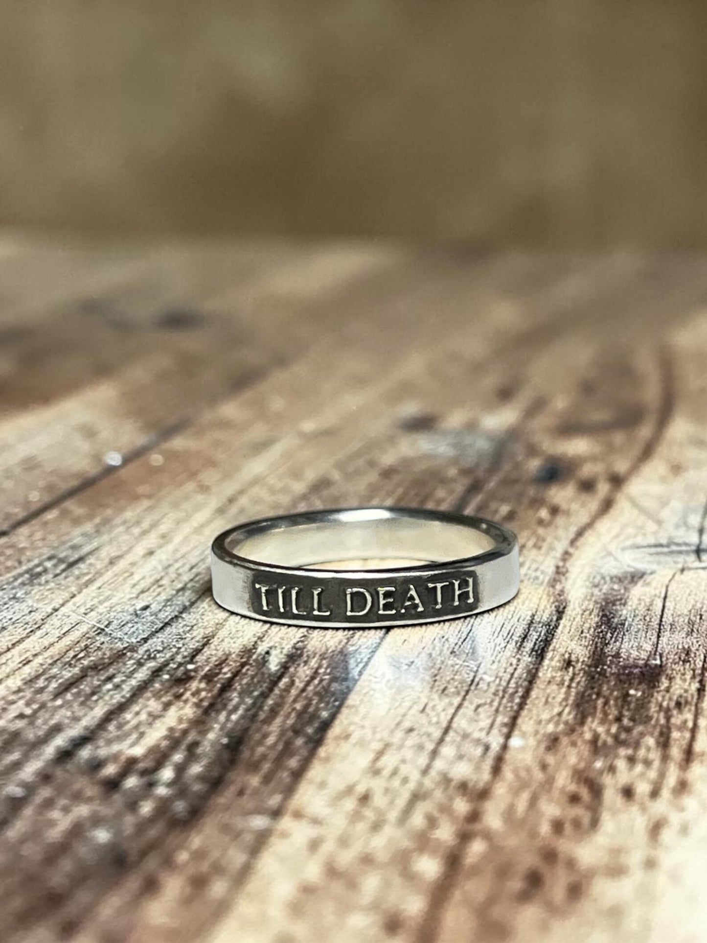 Till Death sterling silver band displayed on wood